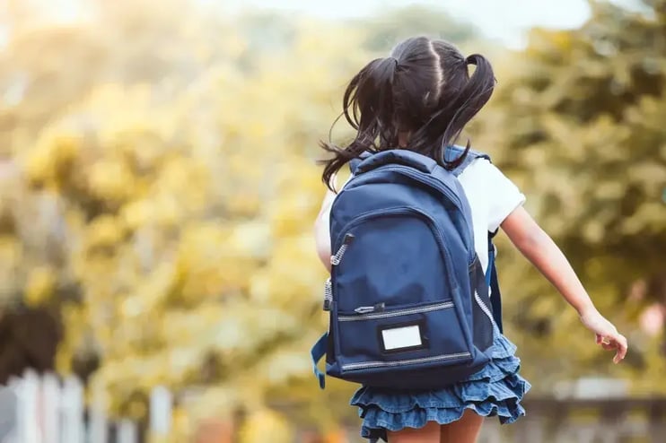 Criança com mochila azul indo para a escola